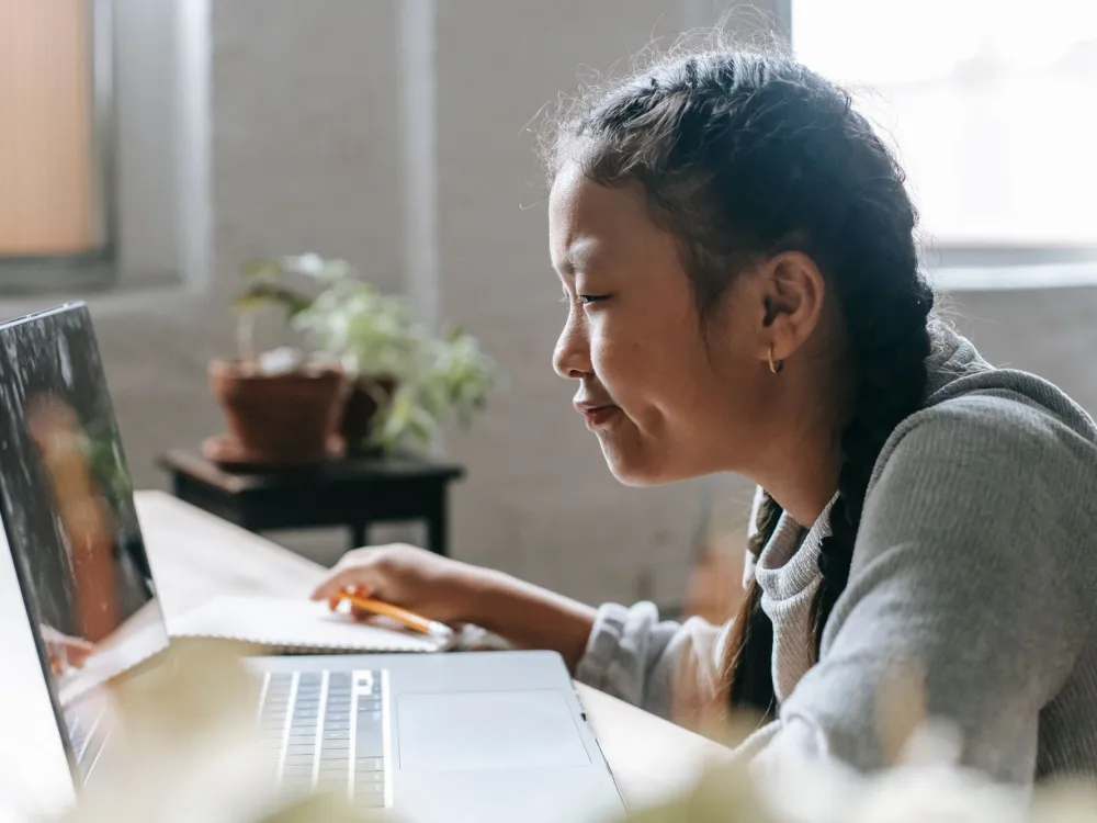 A child coding a project on a laptop during a live class