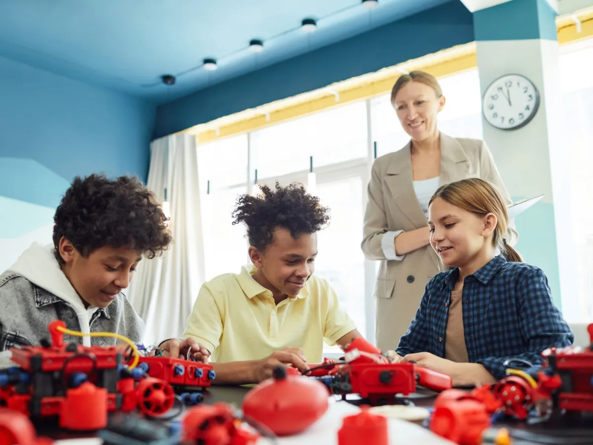 Kids building a robot together while their teacher watches